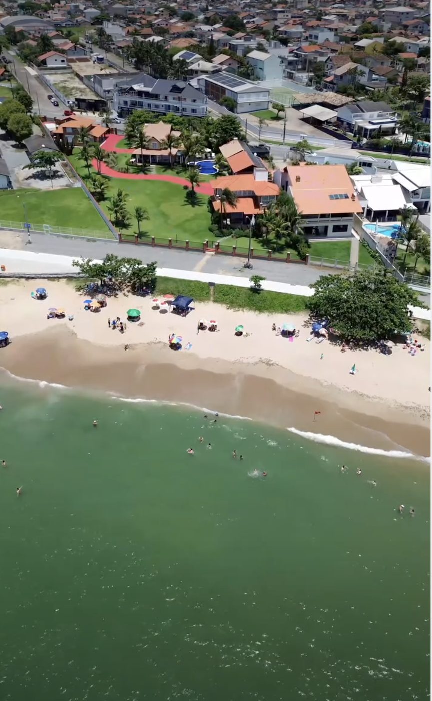 Vista aérea das casas à beira-mar e do calçadão da Praia do Quilombo